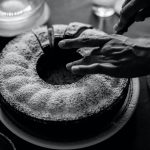 Unrecognizable Hands Cutting Round Cake Sprinkled with Castor Sugar